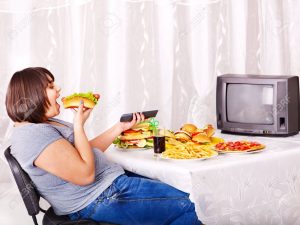 15290486-Sobrepeso-mujer-comiendo-comida-r-pida-y-viendo-la-televisi-n--Foto-de-archivo